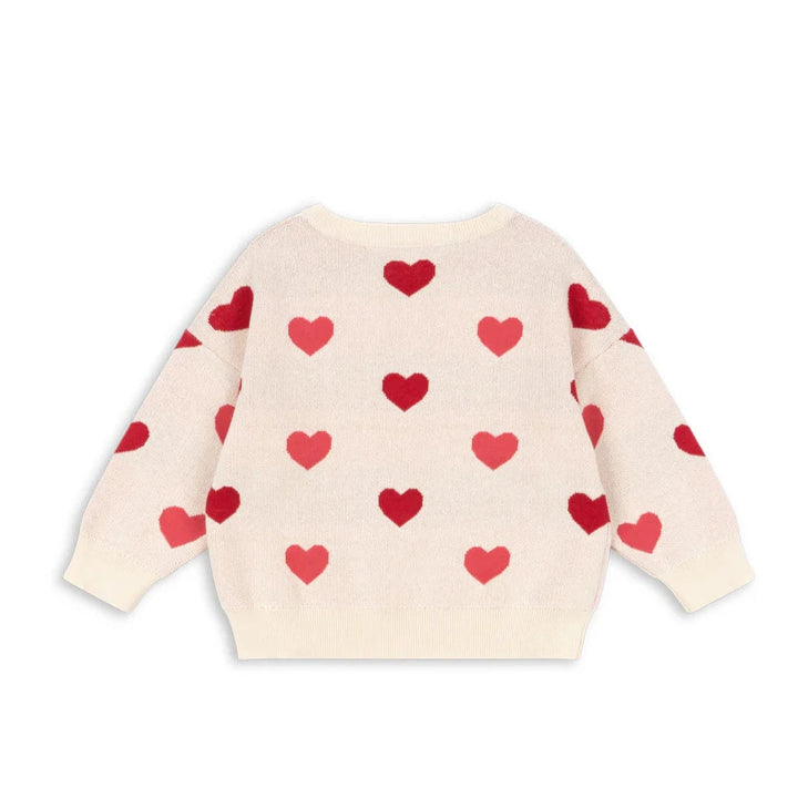 Cream-colored sweater with red heart patterns on a white background